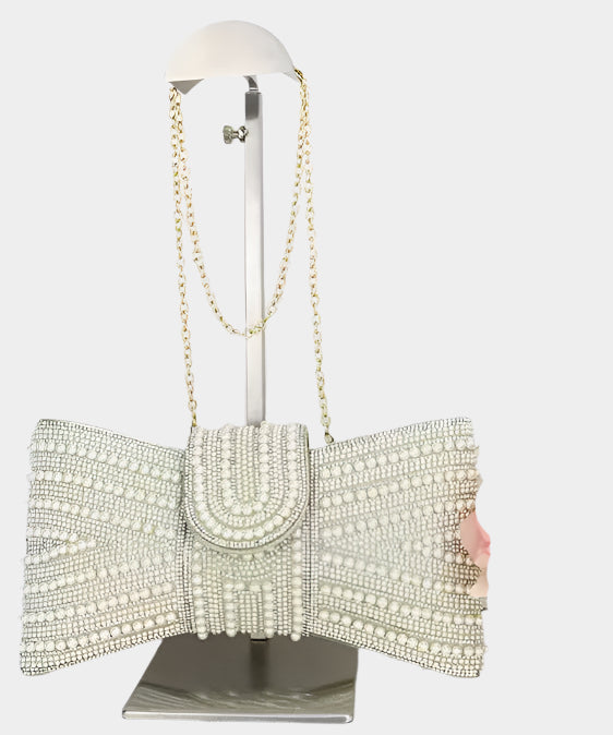 Elegant clutch bag with pearl embellishments on a mannequin stand against a white background
