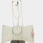 Elegant clutch bag with pearl embellishments on a mannequin stand against a white background