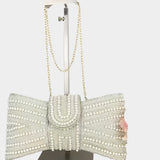 Elegant clutch bag with pearl embellishments on a mannequin stand against a white background