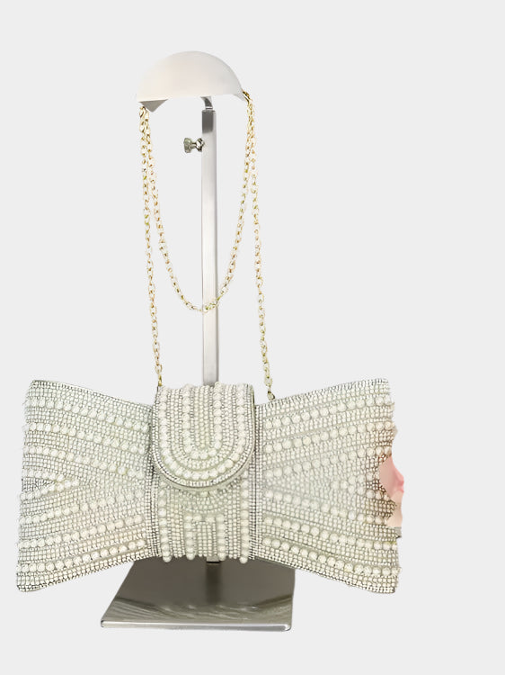 Elegant clutch bag with pearl embellishments on a mannequin stand against a white background